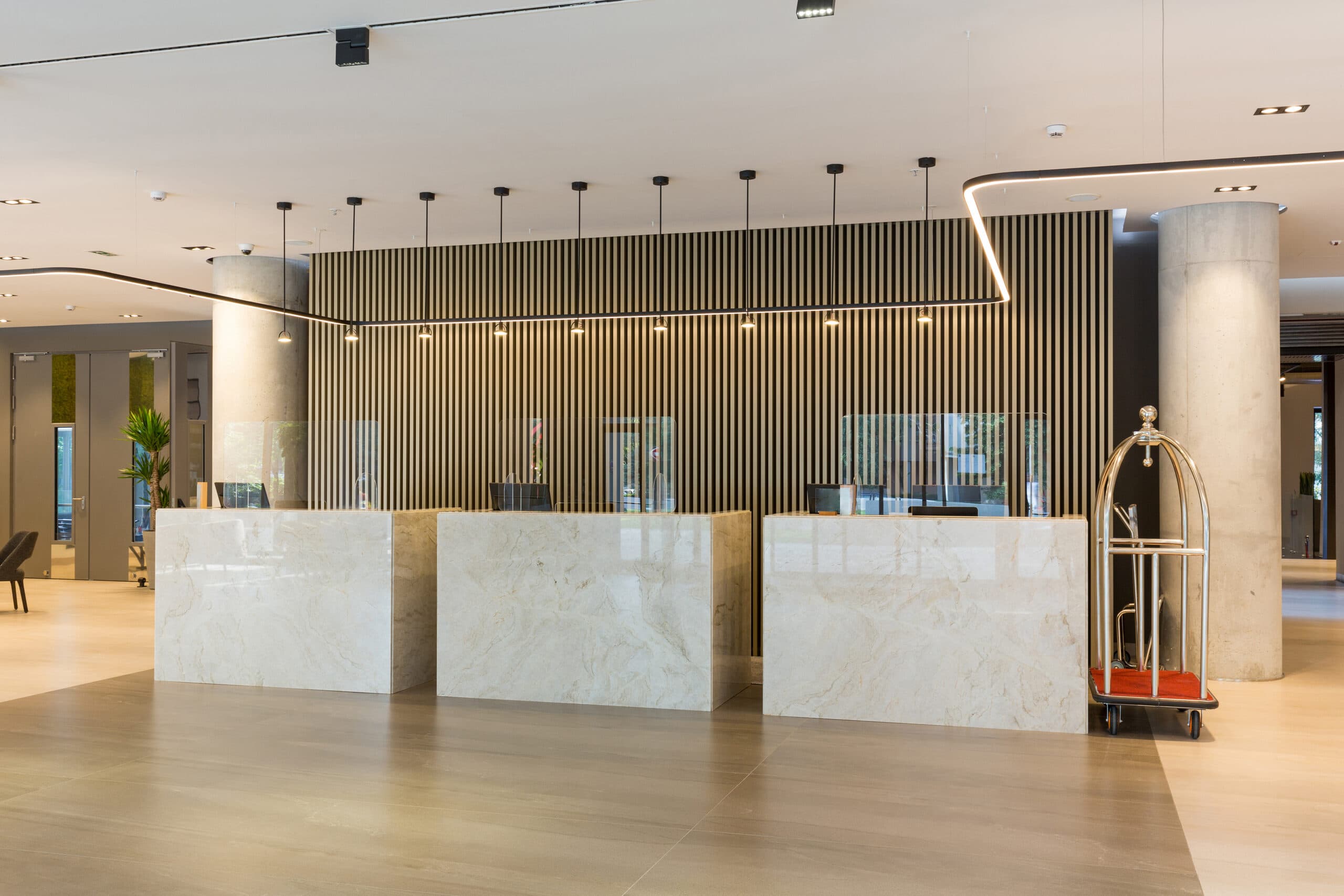 Commercial lobby with linear LED track lighting and pendant fixtures above marble reception desks